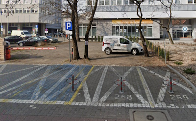 Zdjęcie przedstawia parking dla aut przed budynkiem WARP